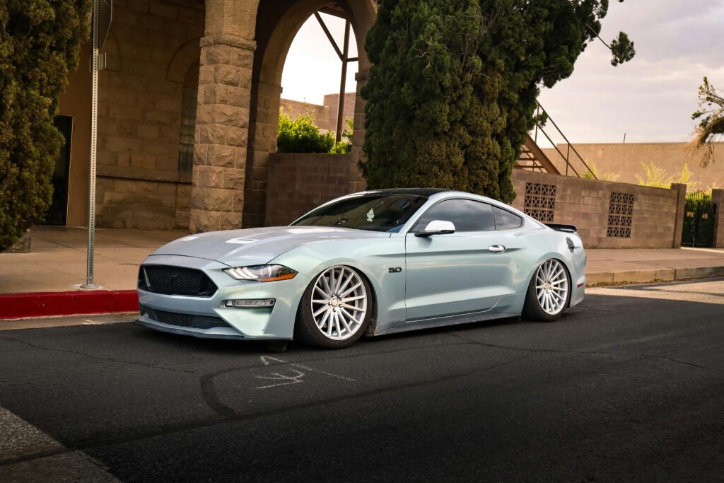 pexels-photo-32828586-32828586 Silver sports car with stylish rims parked on an urban street corner during the day.